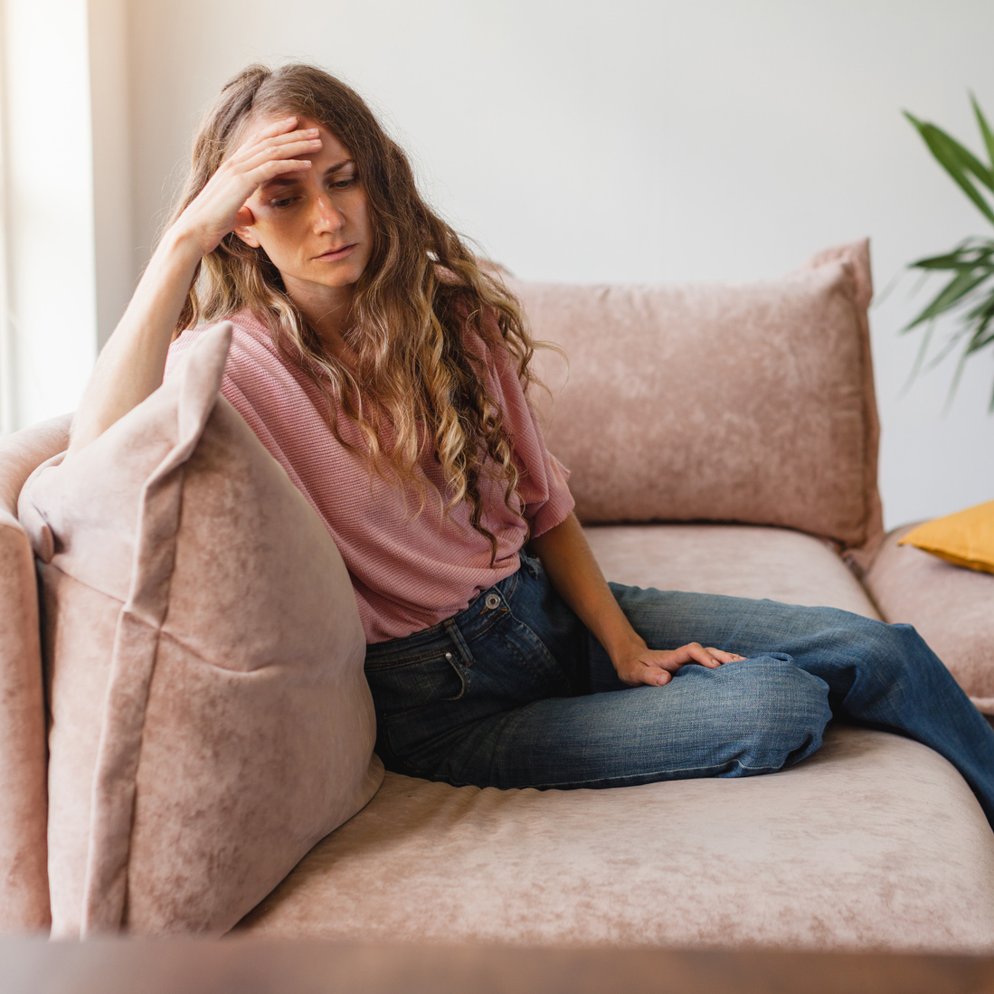 Sad woman thinking about problem, sitting alone on couch